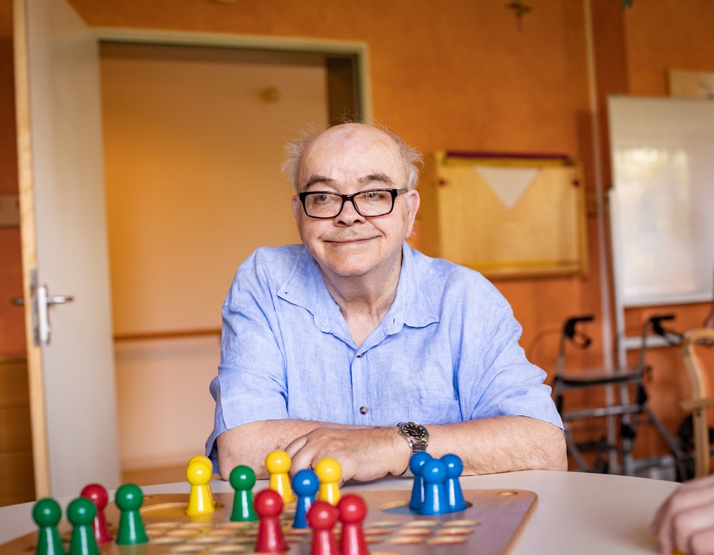 Ein Bewohner vor dem Brettspiel "Mensch-ägere-Dich-nicht".