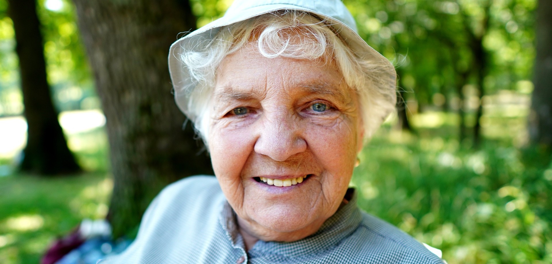 Eine lächelnde alte Dame, im Hintergrund befindet sich eine Grünanlage. Bild: pixabay